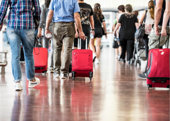 People in airport pulling red suitcases