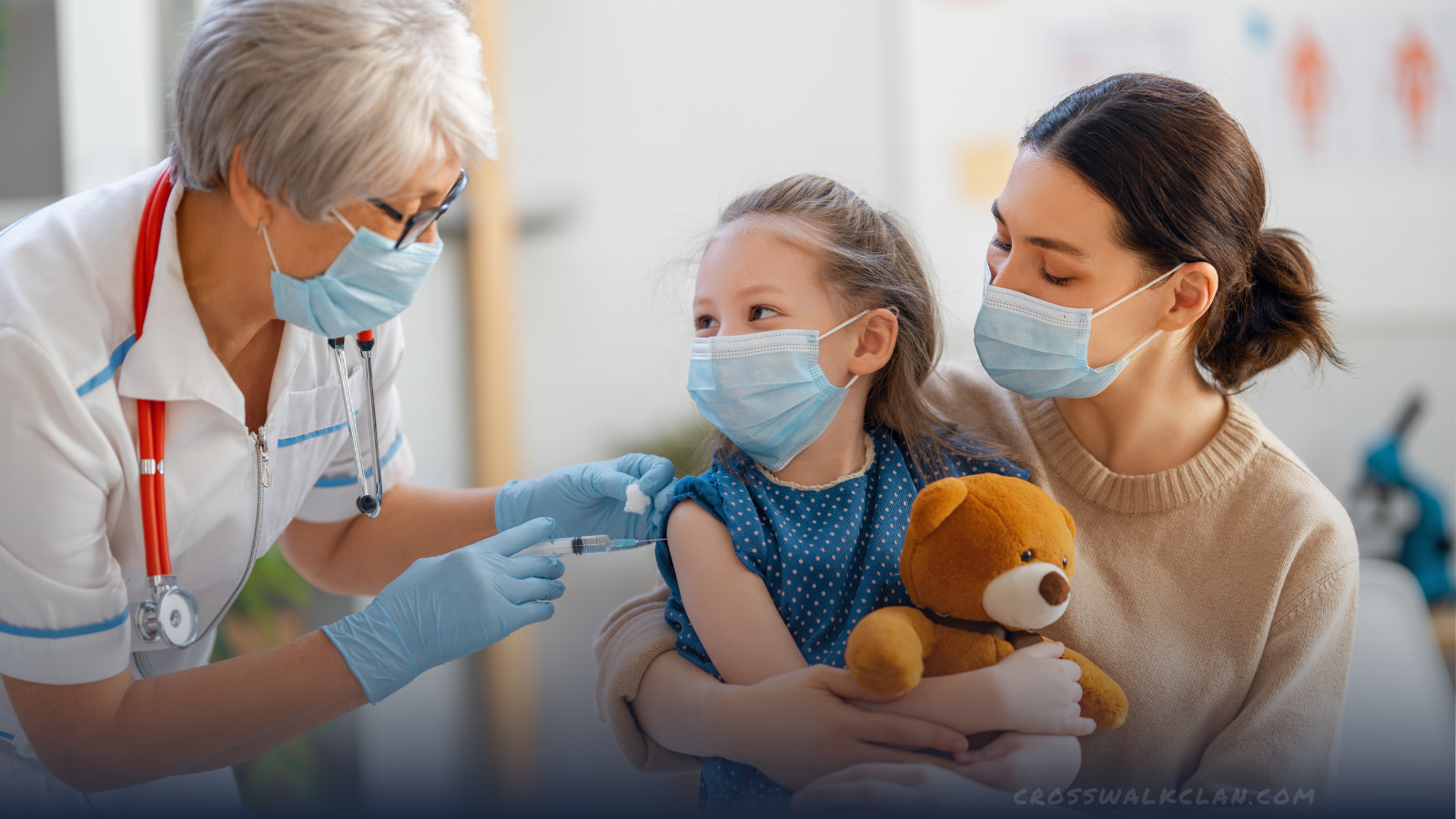 Smiling young masked girl getting a COVID vaccine with her masked Mum and a grey haired masked nurse